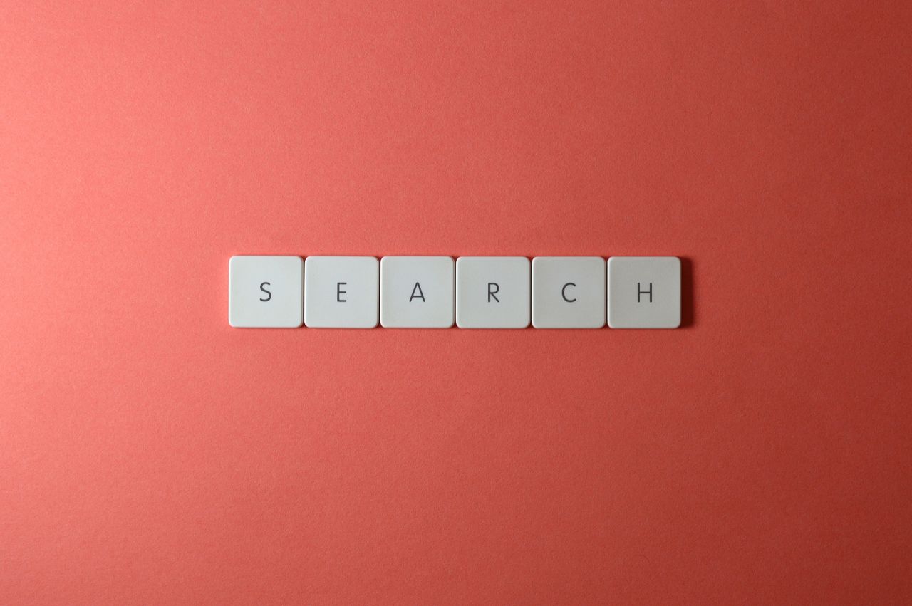 White keyboard keys spelling search on a bold red surface, conceptual design with copyspace.